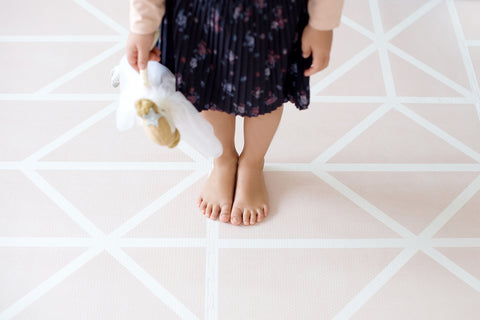 young girl with bare feet standing on a playmat