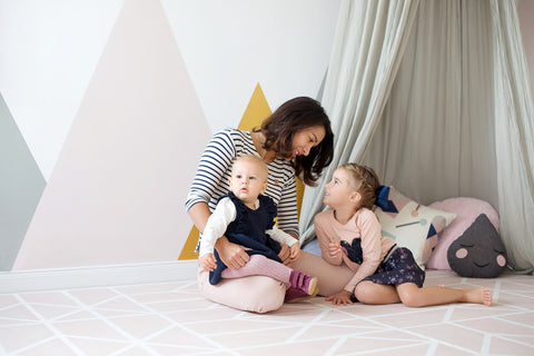 mother and two daughters sitting on a playmat