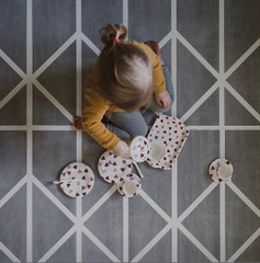 Young girl sitting on a playmat having an imaginary tea party